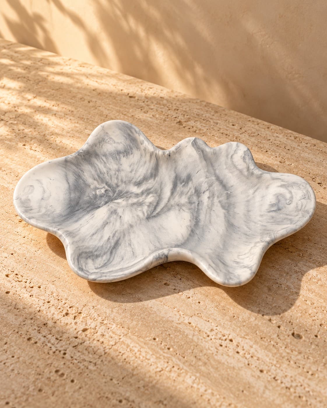 Large cloud-shaped marble tray in black marble, shown on a travertine surface