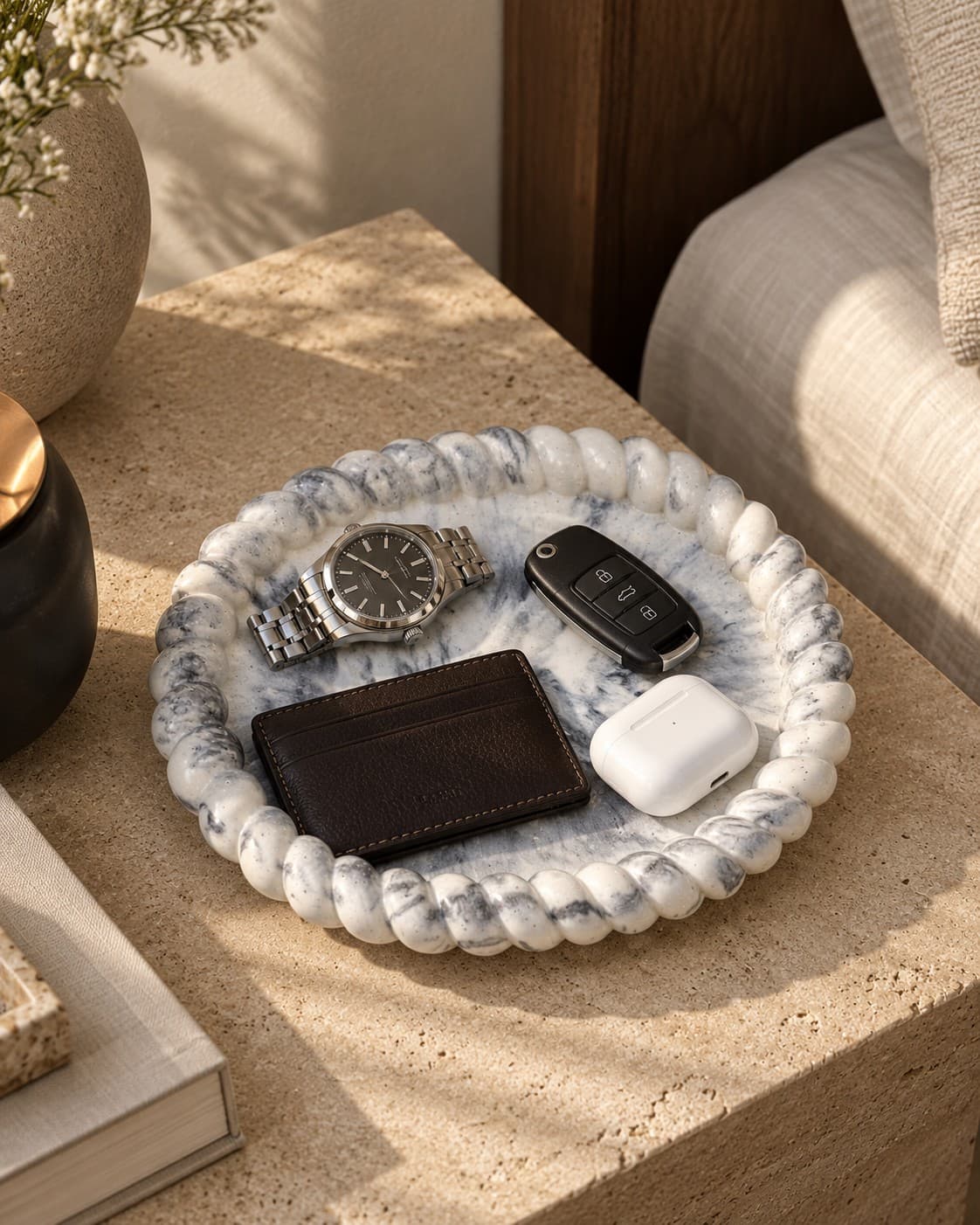 Small oval marble tray in black marble, styled on a bedside table with a watch, keys and wallet